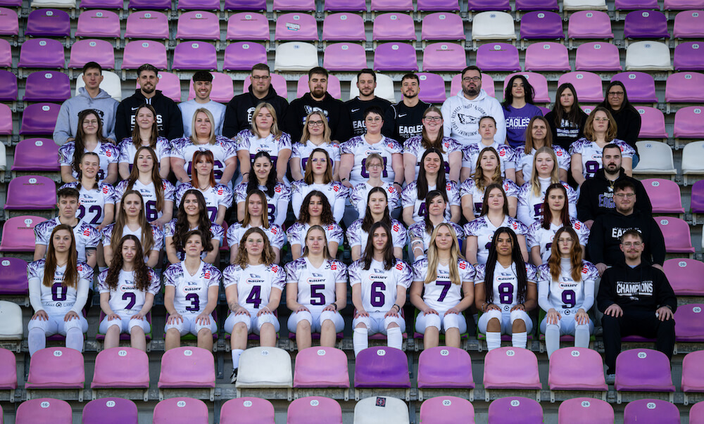 reutlingen-eagles-ladies-teamfoto-2025 Mannschaftsfoto des American Foorball Ladies Team der Reutlingen Eagles mit weißen Trikots und lila Sitzen.